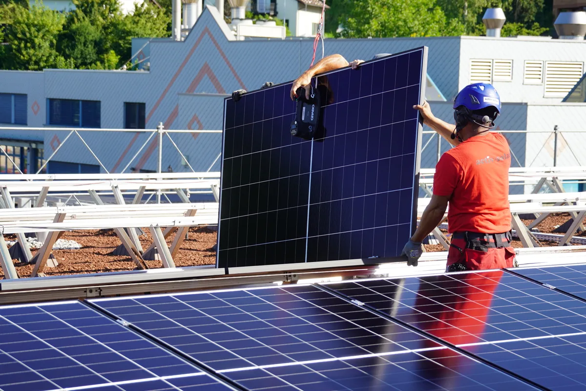 Zwei Bauarbeiter nehmen ein Panel entgegen.